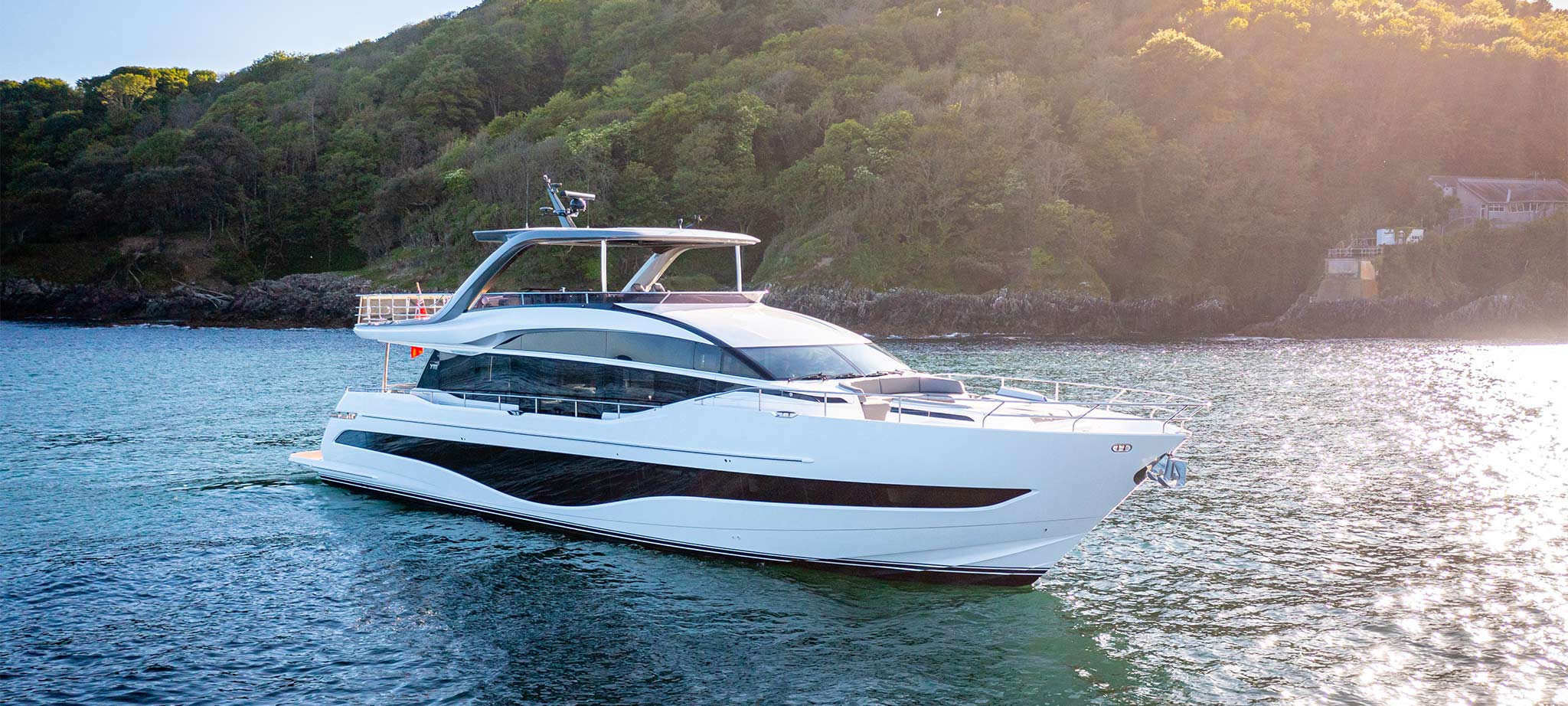 A luxury cruising yacht anchored off the coast of a tropical island.